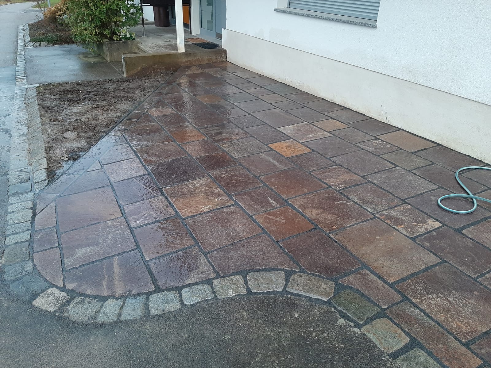 Vorplatz mit Porphyr-Natursteinbelag und Granit-Bogenfassung