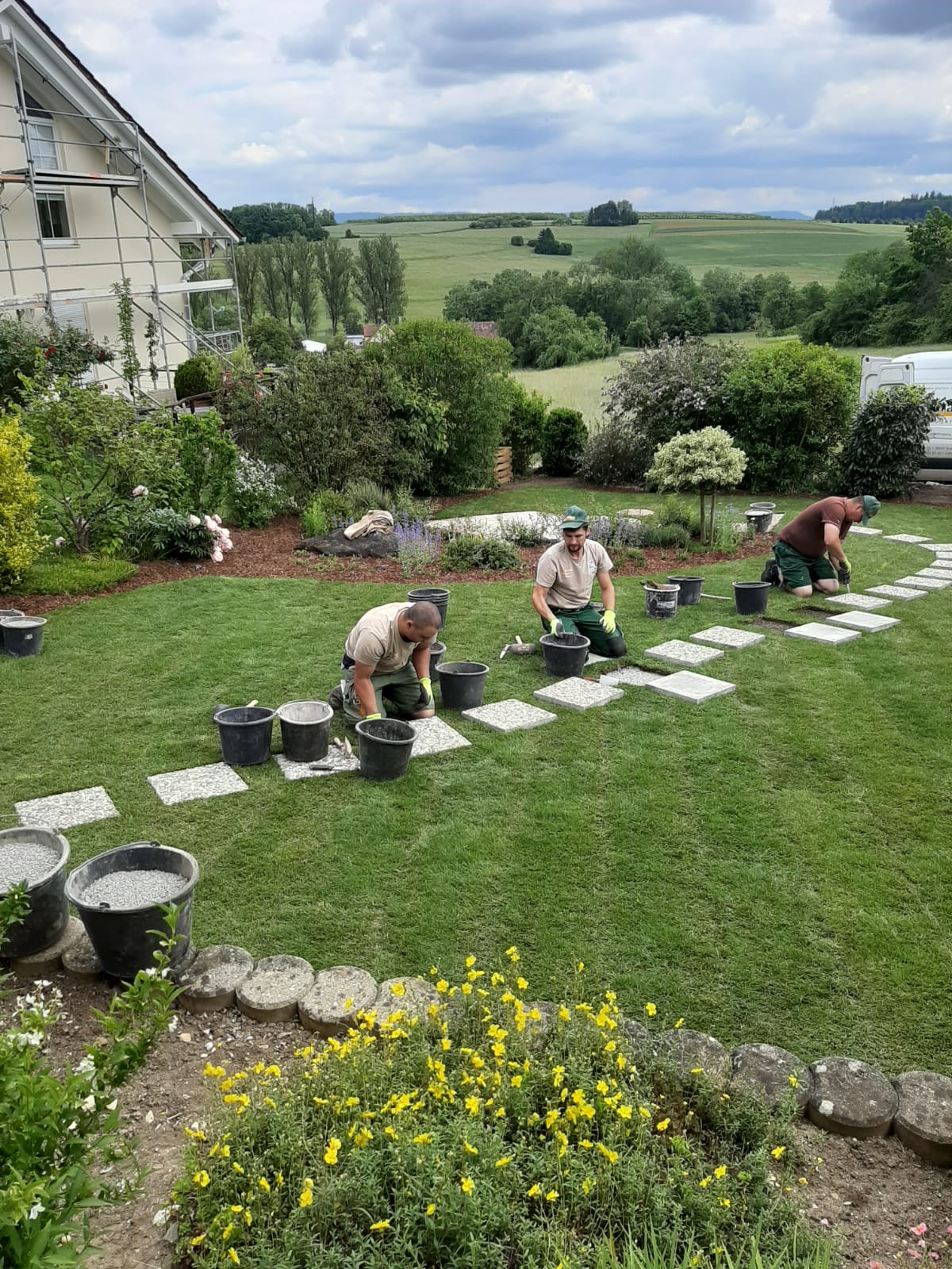 Gartenbauarbeiten beim Einbau und Ausrichten der Trittplatten im Rasen.