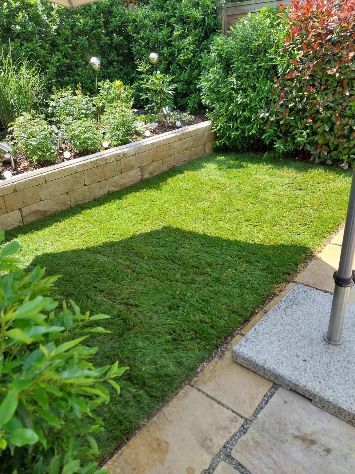 Privatgarten mit Natursteinmauer, Terrasse und Rollrasen in Nürtingen