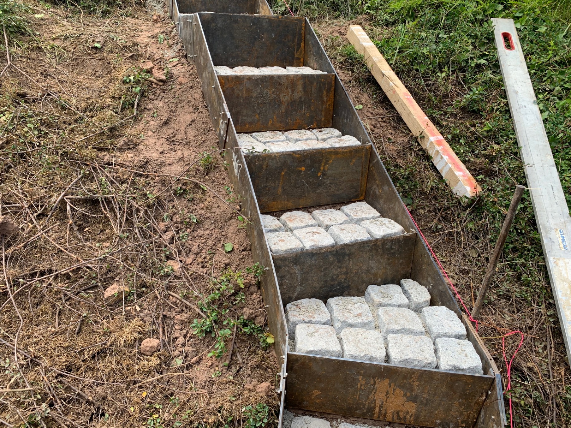 Bauphase der Hangtreppe mit eingesetzten Natursteinpflaster-Steinen in der unteren Treppenführung