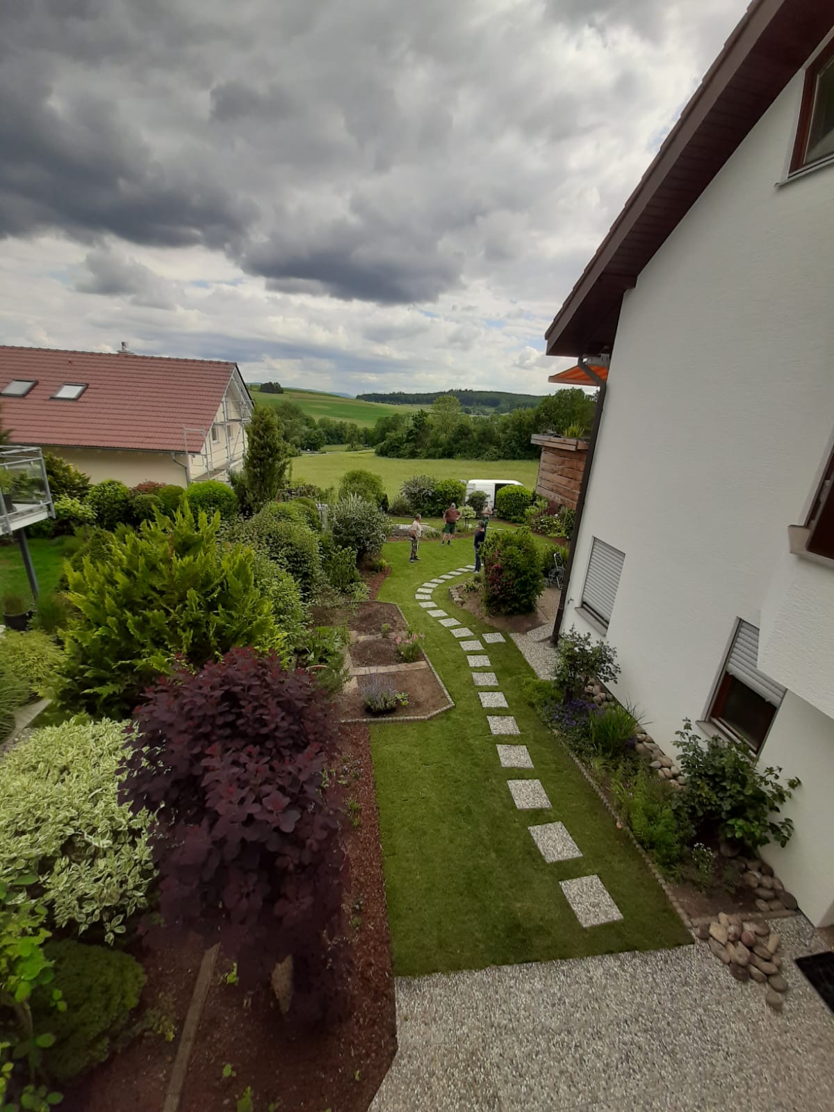 Wegverlauf aus Trittplatten entlang des Hauses mit angrenzender Rasenfläche.