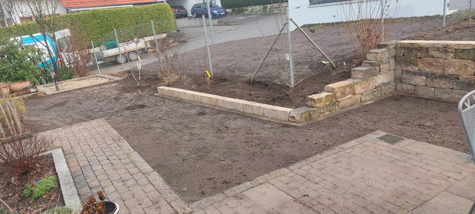 Gartenanlage mit Terrassierung am Hang und vorbereiteter Fläche für Hochbeet und Gartenhütte