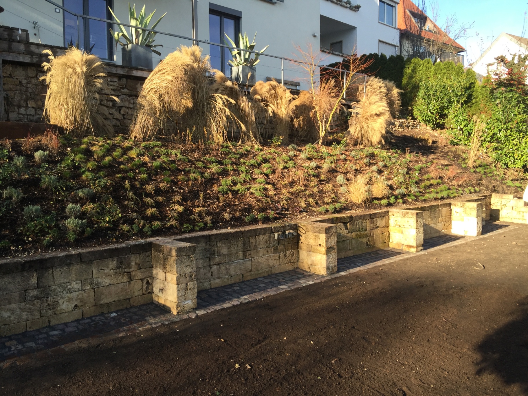 Hangbereich mit Natursteinmauer, Gräsern und Staudenpflanzung